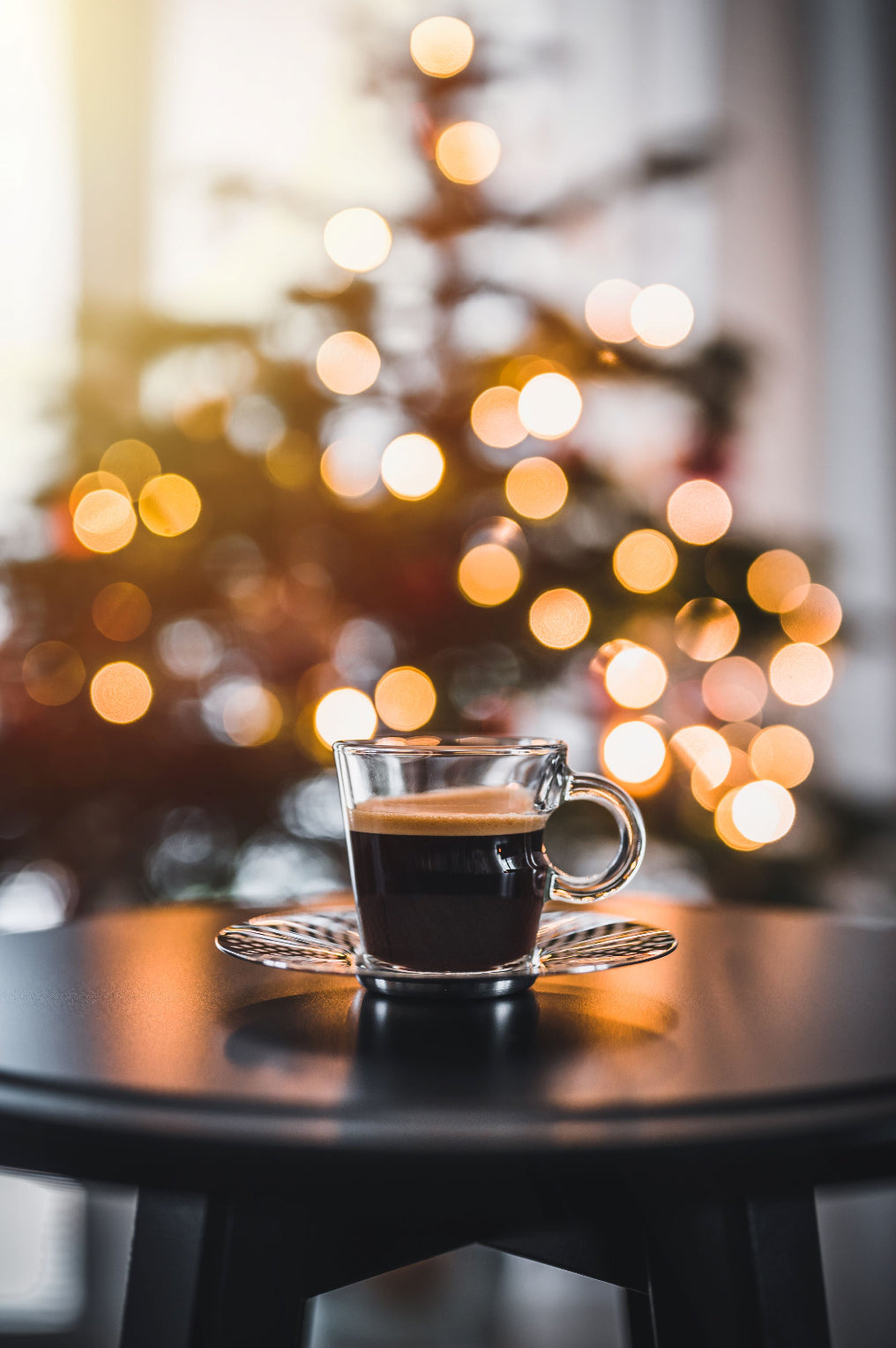 A cup of Tropical Bear Santa's Favorite Blend Specialty Coffee on a table with a Christmas tree in the background.