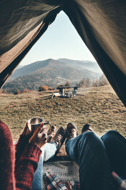 Two people in a tent drinking Elevation Kick coffee and looking at a mountain.