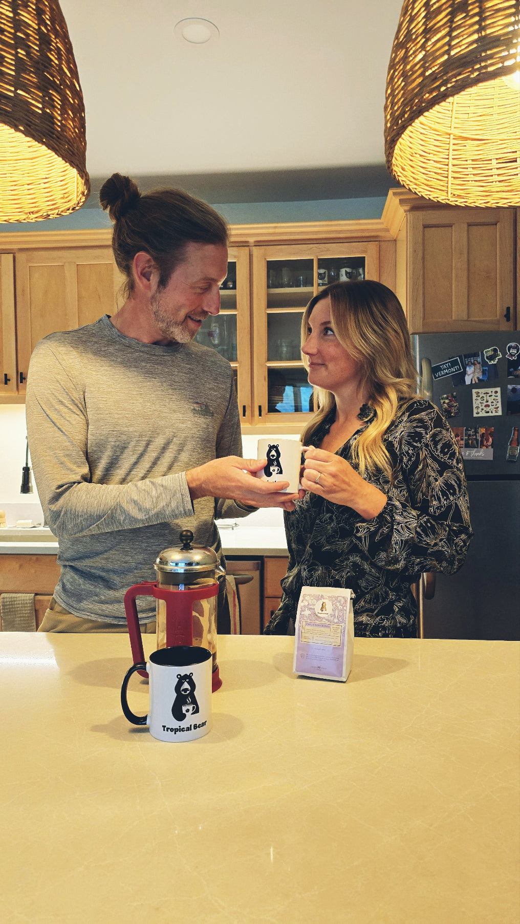 Austin is giving Monica a cup of Papua New Guinea single-origin organic coffee in their kitchen after using a French press. 