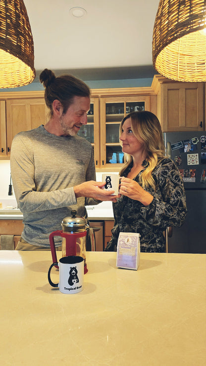Austin is giving Monica a cup of Papua New Guinea single-origin organic coffee in their kitchen after using a French press. 