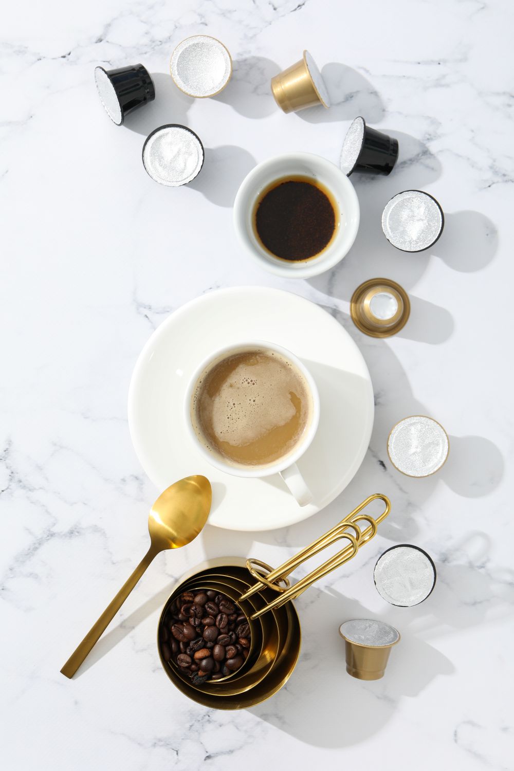 Coffee cups, coffee beans, and coffee-making tools on a marble surface
