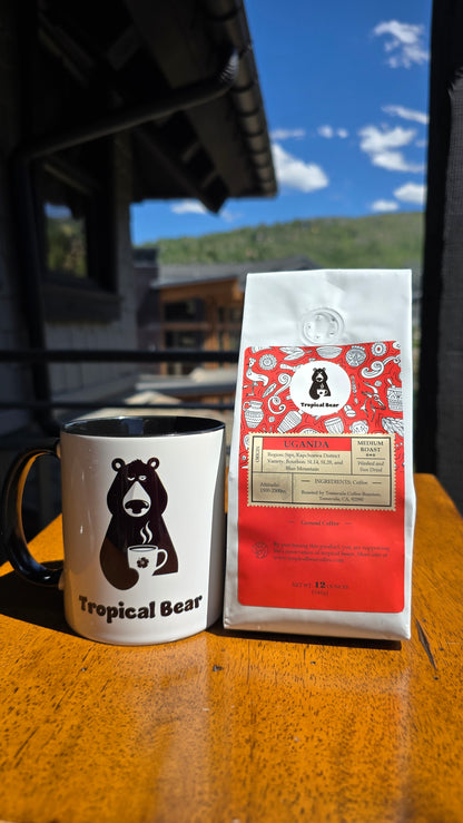 The bag of Uganda single-origin organic coffee is next to the tropical bear mug. Fresh coffee delivered to your door! 