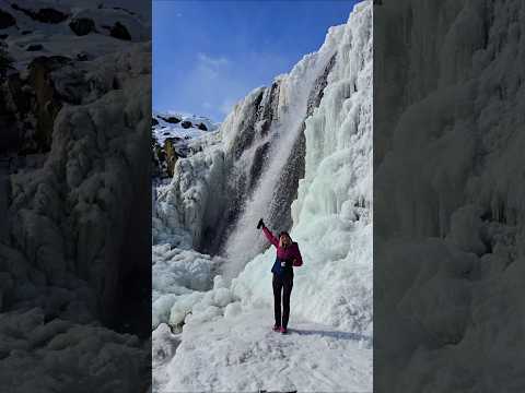 Erica Leafe holding a coffee mug next to a frozen waterfall in Mongolia.