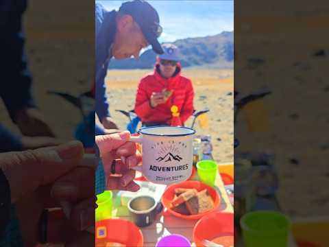 Erica holding a coffee mug at an outdoor lunch table in Mongolia. 