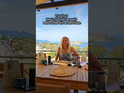 A reel showing Erica Leafe brewing coffee with an Aeropress on a balcony on an island in Greece. 